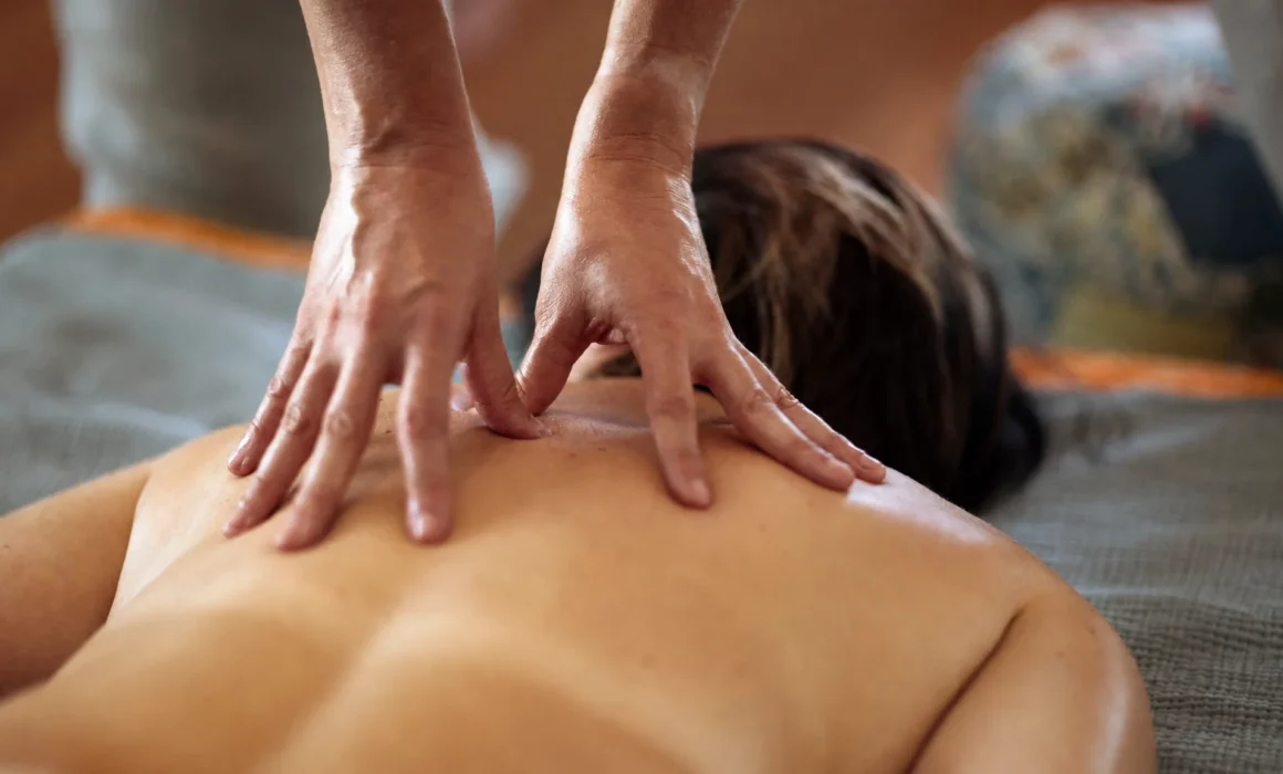 Gros plan d’un massage du haut du dos réalisé sur une personne allongée
